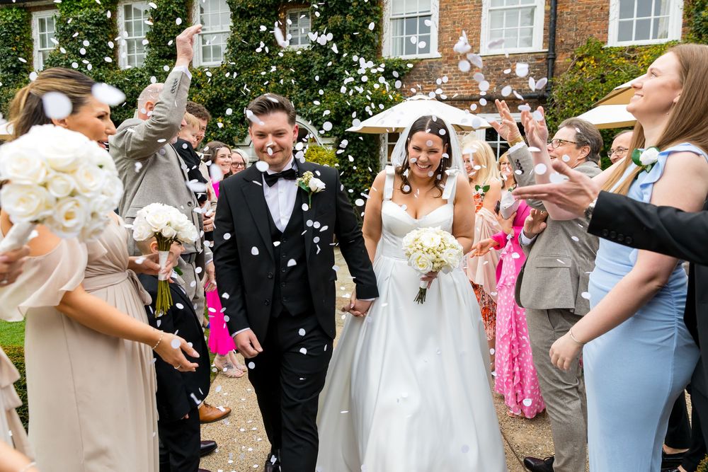 Confetti shower over smiling bride and groom at Bush Hotel wedding