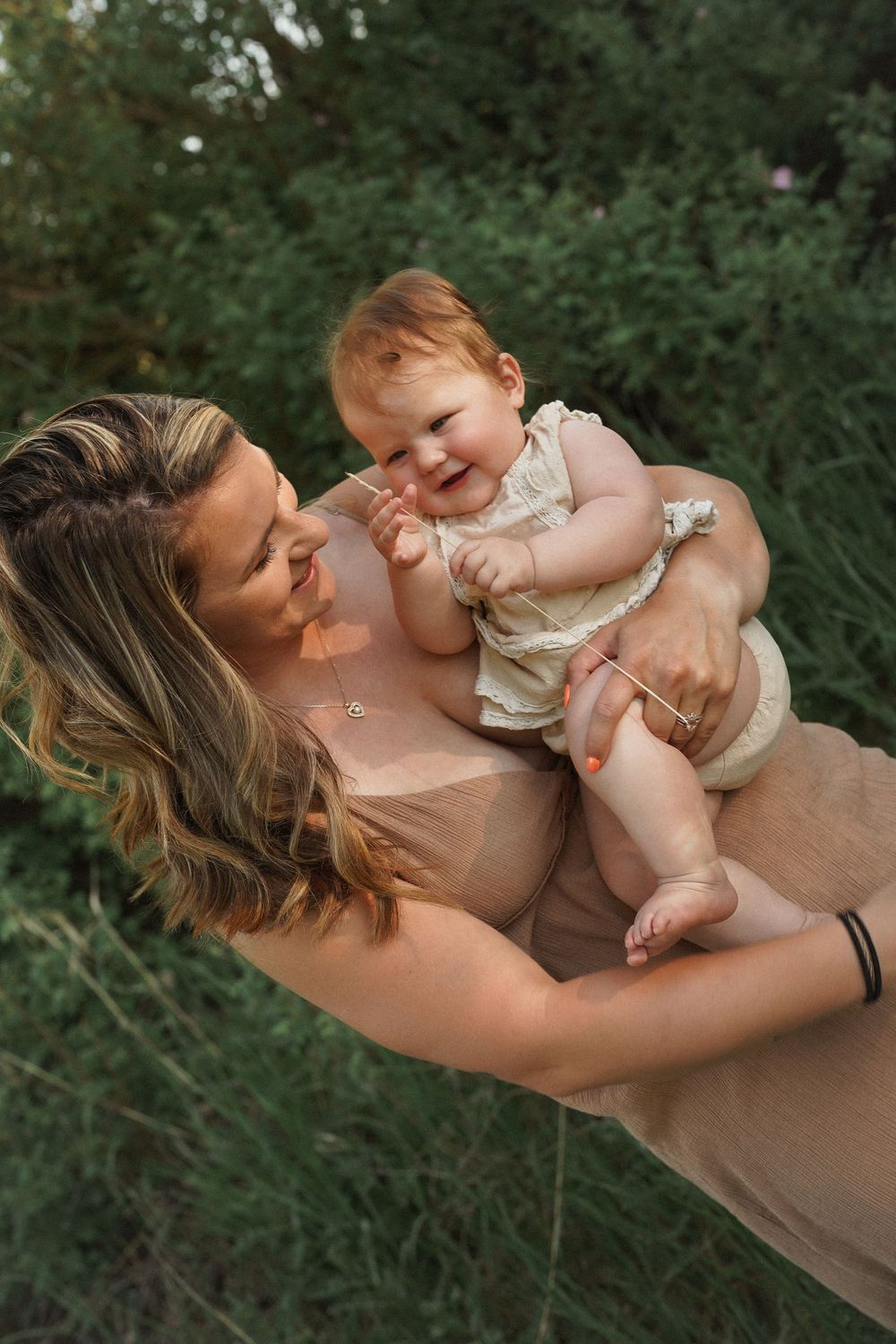 A tender outdoor moment captured in warm light wearing a beige dress with lace details.
