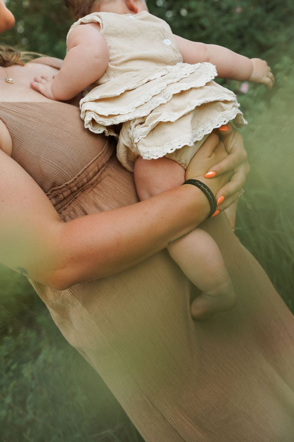 Close-up detail of cream-colored ruffled clothing against a beige dress in an outdoor setting.