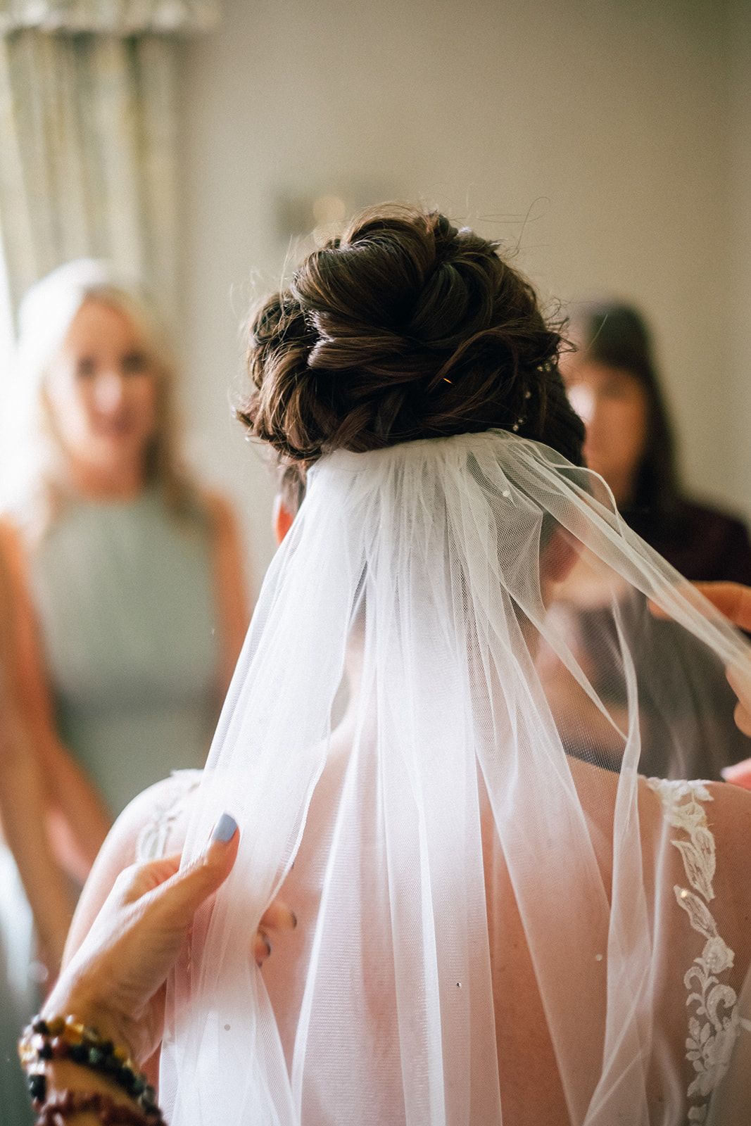 Close up view of a wedding hairstyle with delicate veil being styled at a bridal preparation.