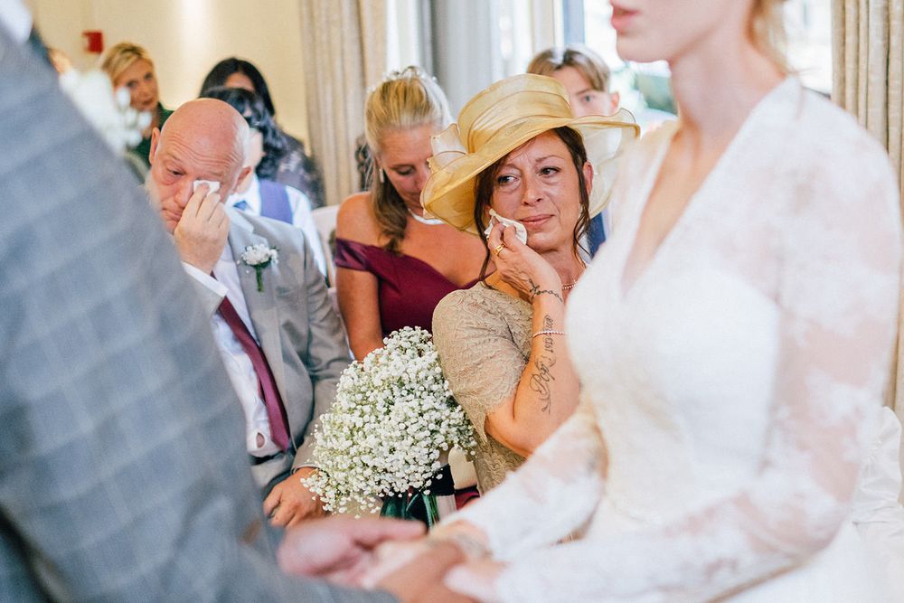 Emotional wedding ceremony moment captured with guest holding baby's breath bouquet.