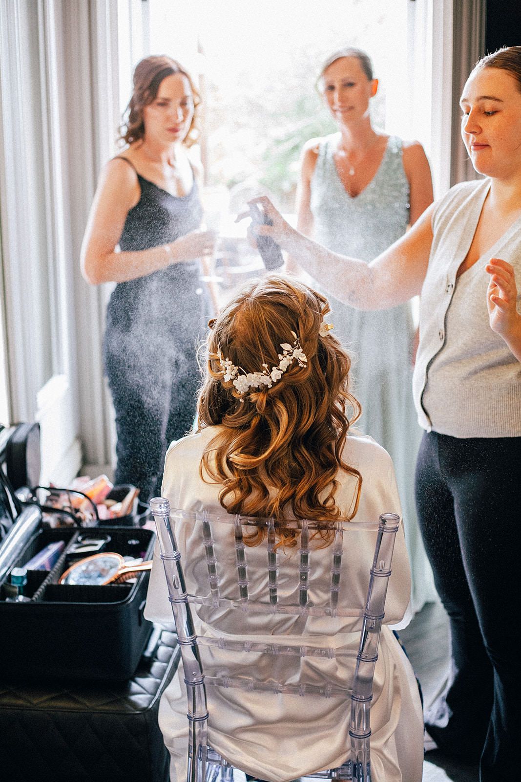 Wedding preparation scene with bridesmaids getting ready in a sunlit room.