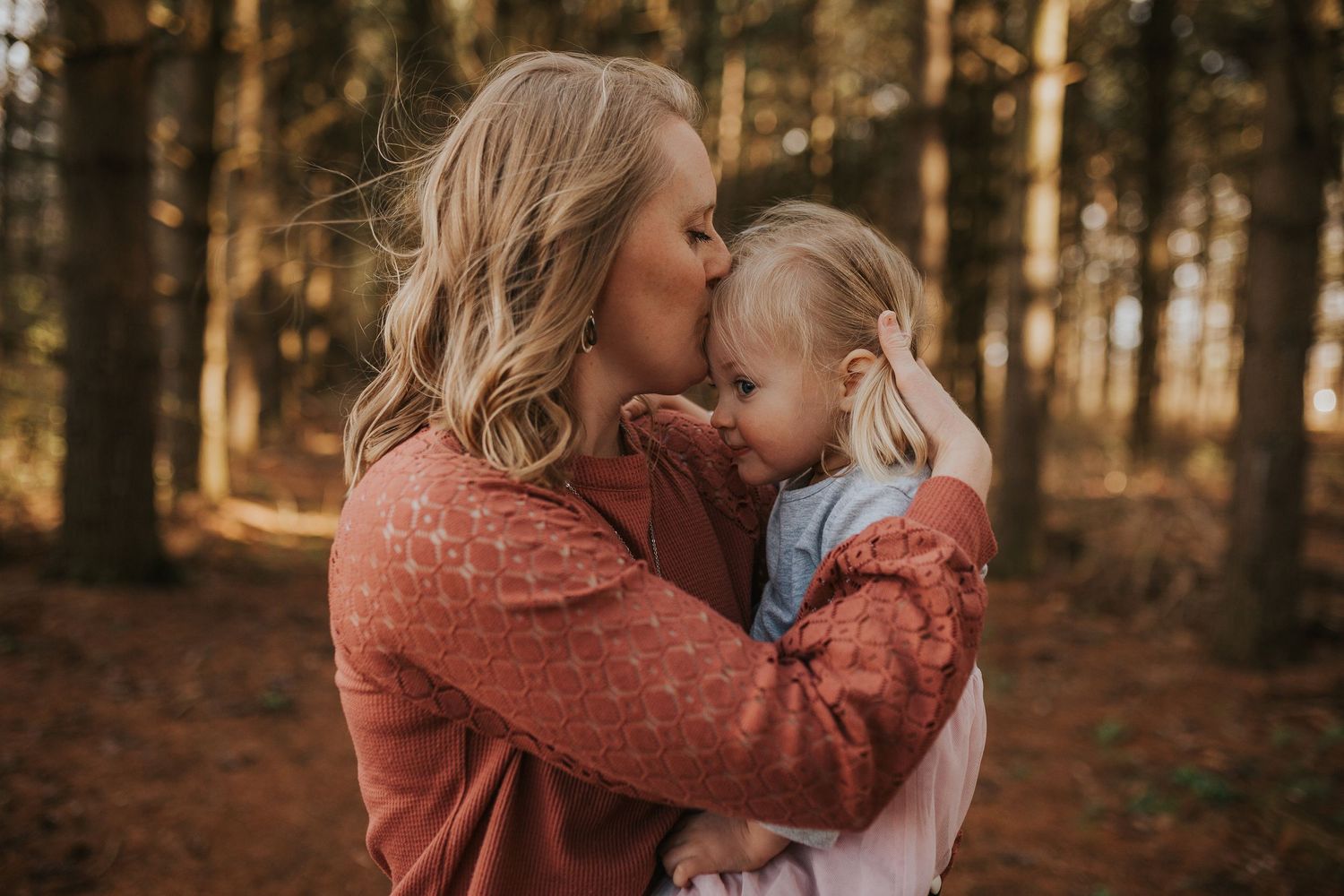 Tender moment captured between parent and child in autumn forest setting.