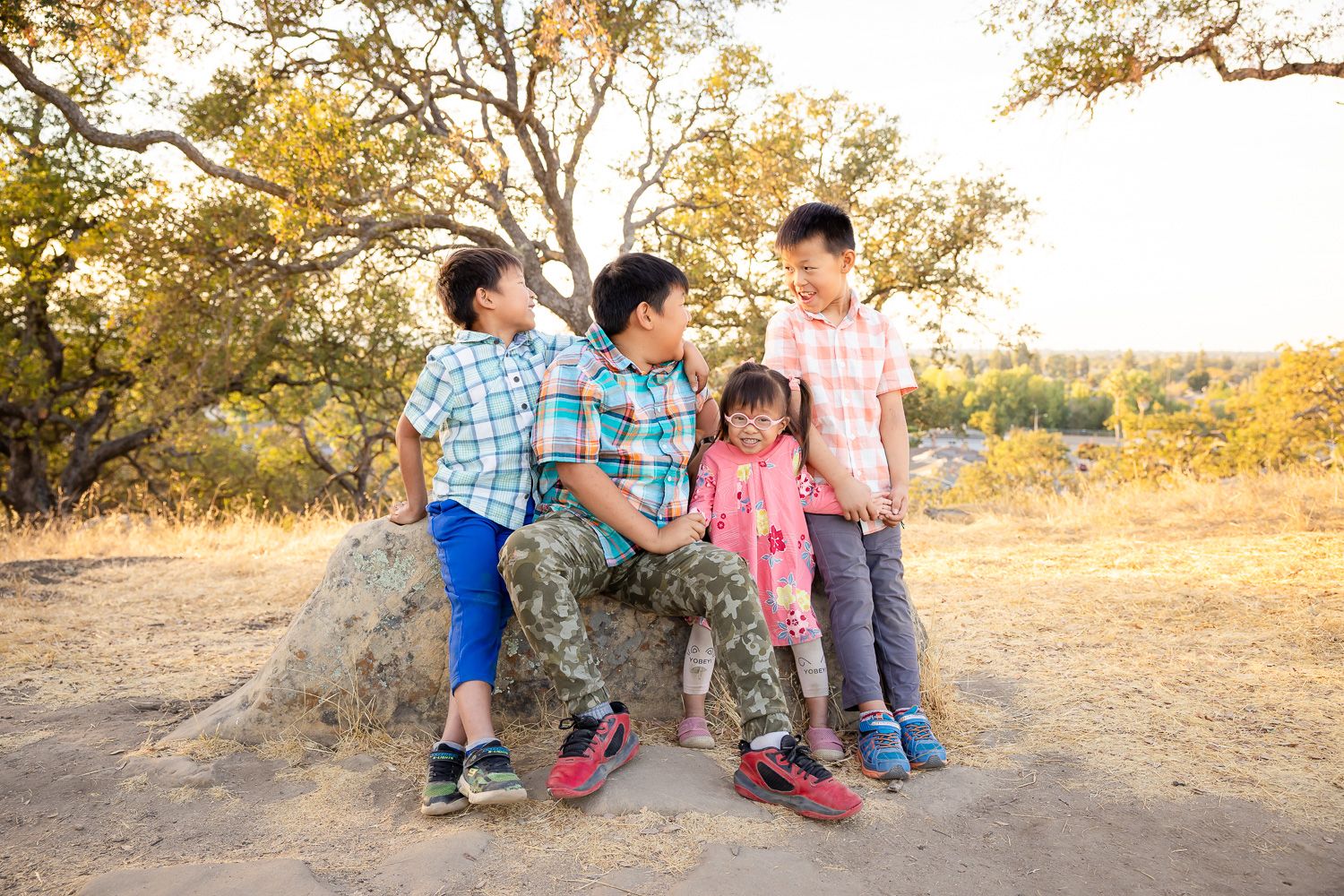Kids sit on rock during photography session with Bay Area Photographer Cindy Tucey in San Jose