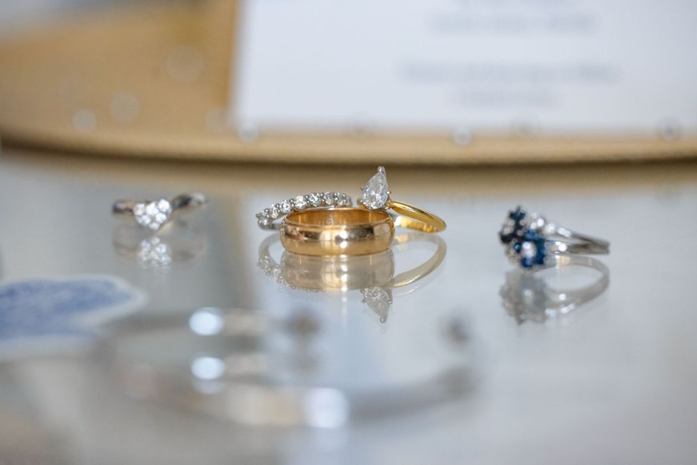 Close-up of elegant wedding rings and jewelry arranged on a reflective surface.