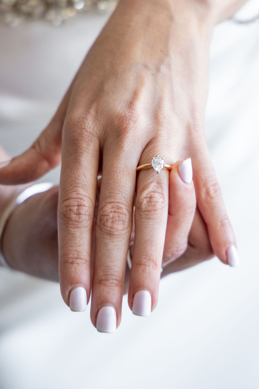 Close-up of a perfectly manicured hand displaying a sparkling engagement ring.