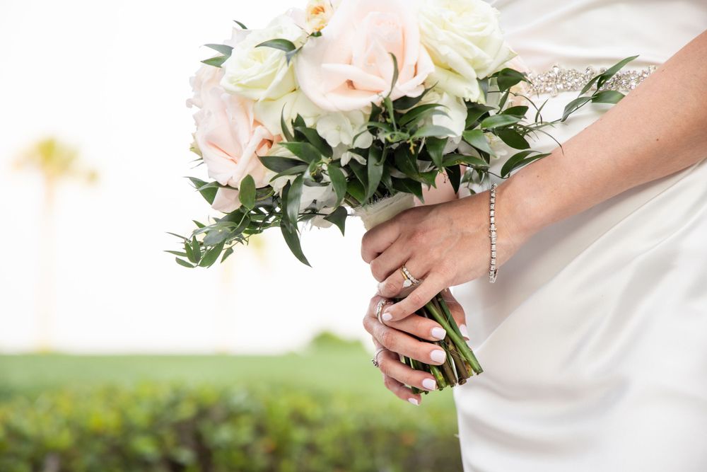 Close-up of bridal bouquet with pink and white roses against white wedding dress.
