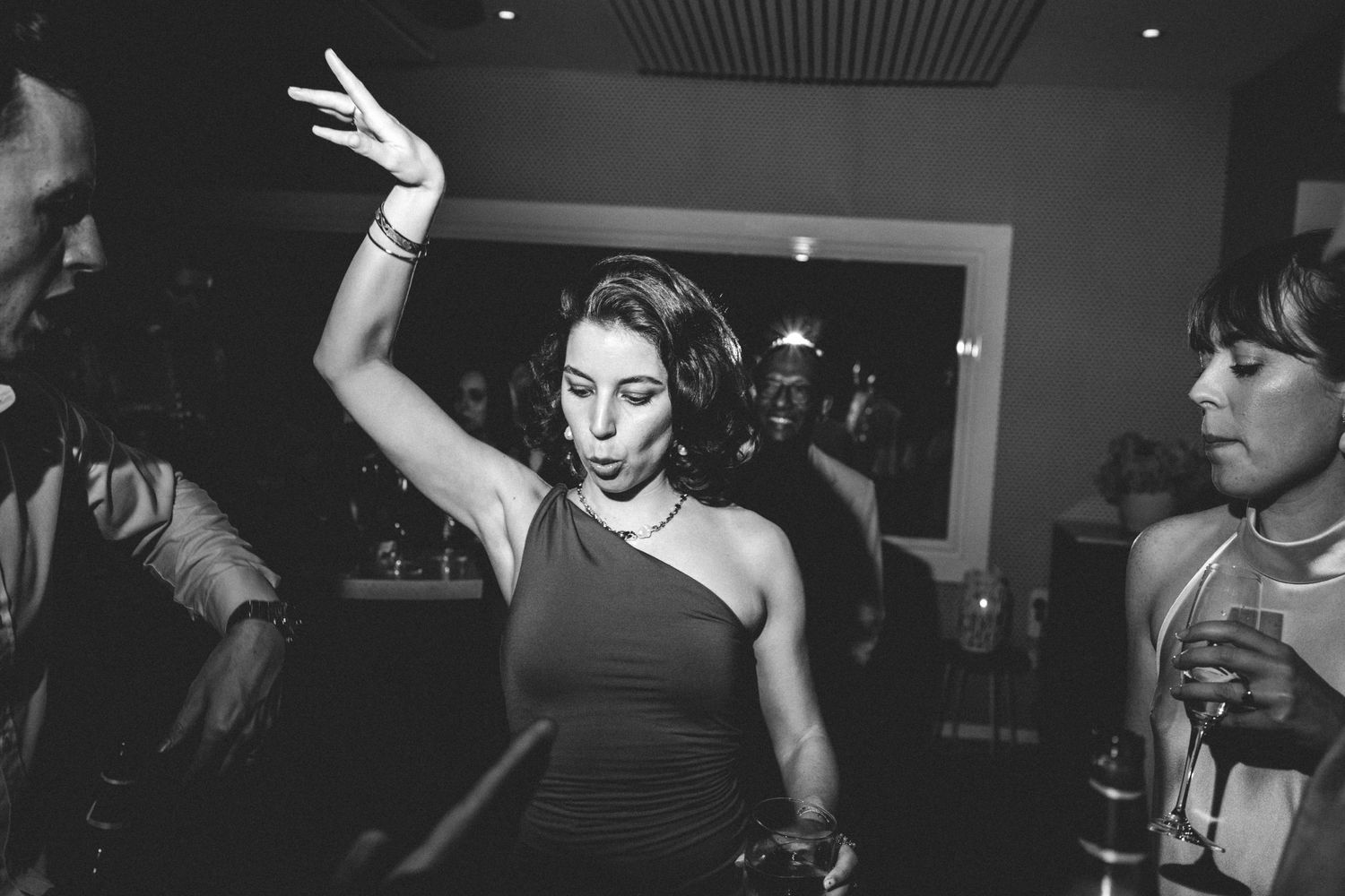 A woman in a dark dress dances with raised arm at a nighttime celebration.