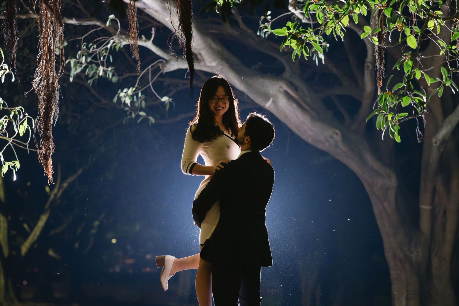 Engagement photo session in front of ornate stone archway with greenery.