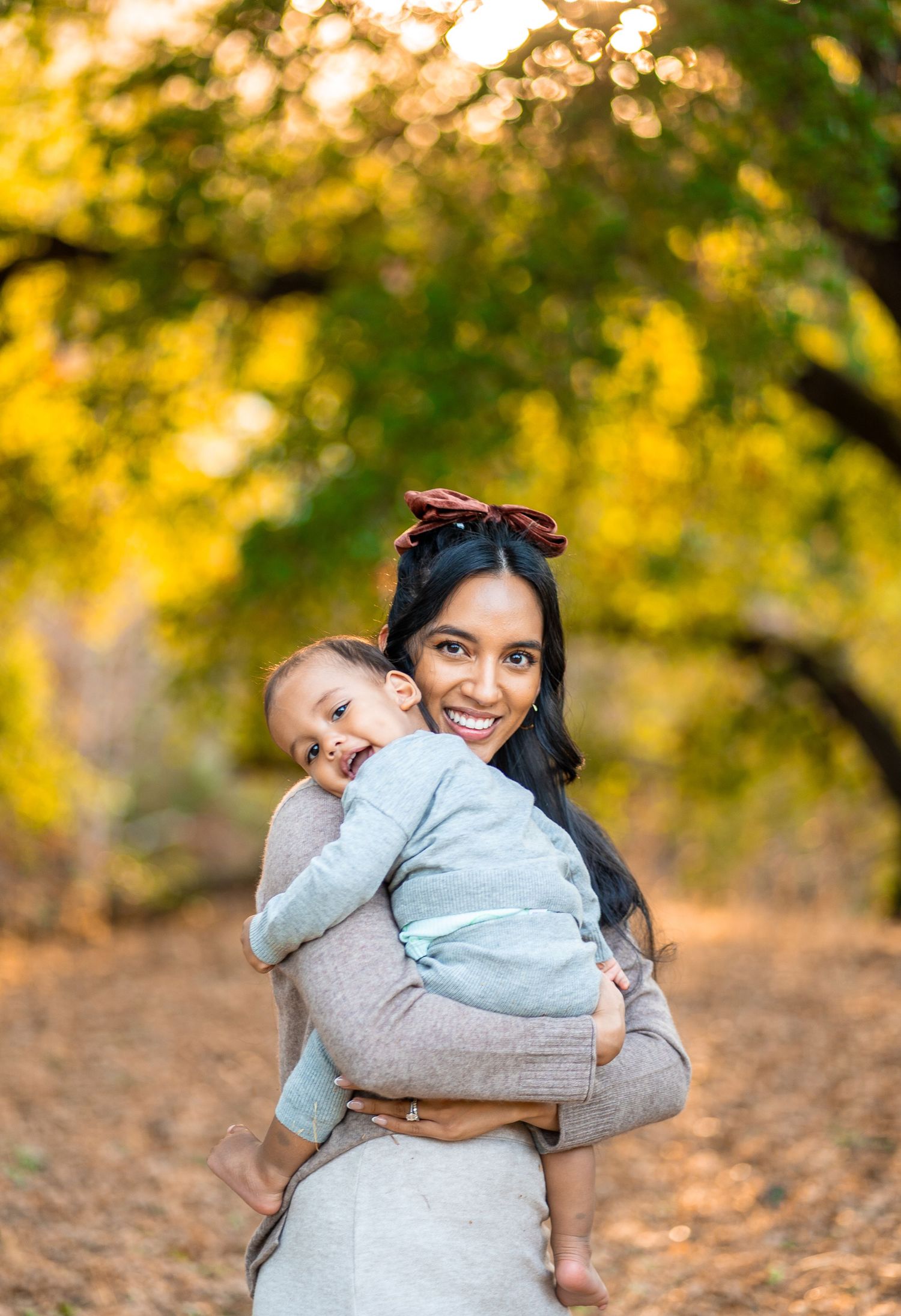 Playful autumn portrait against golden bokeh background of trees and falling leaves.