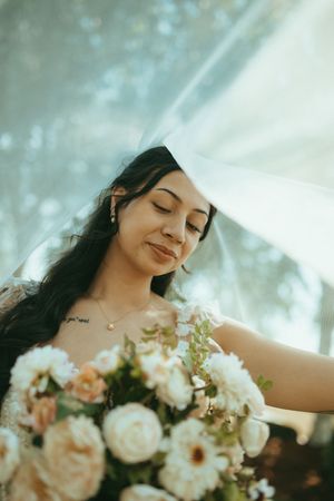 An ethereal wedding portrait features delicate peach and white floral arrangements in soft, dreamy lighting.