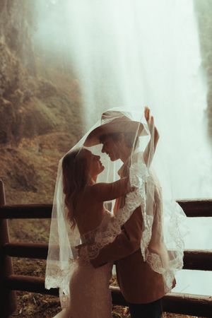 A romantic silhouette of a couple under delicate white lace veil creates a dreamy wedding moment.