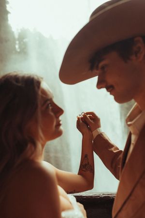 A romantic vintage-style photo of a couple in warm lighting, with a cowboy hat silhouette and clasped hands between them.