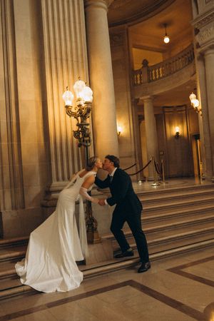 A series of romantic wedding photos showing a couple dancing and dipping in a grand marble hallway with classical columns.