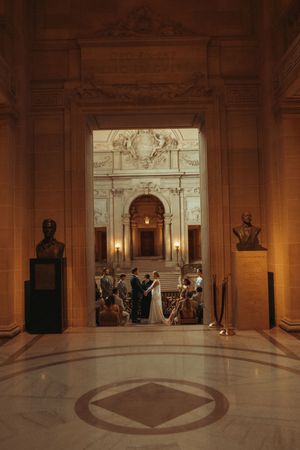A panoramic view of the interior rotunda at San Francisco City Hall with marble columns and ornate architectural details.