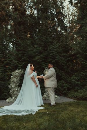 A bride and groom share a tender first look moment among evergreen trees during their outdoor wedding ceremony.