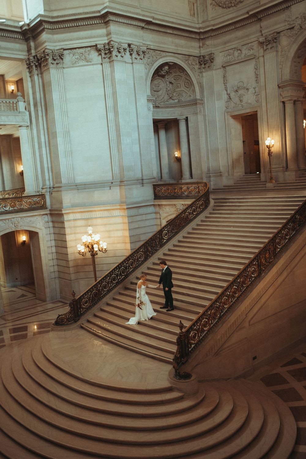 Elegant marble staircase in San Francisco City Hall with ornate railings and warm lighting creates a grand architectural view.