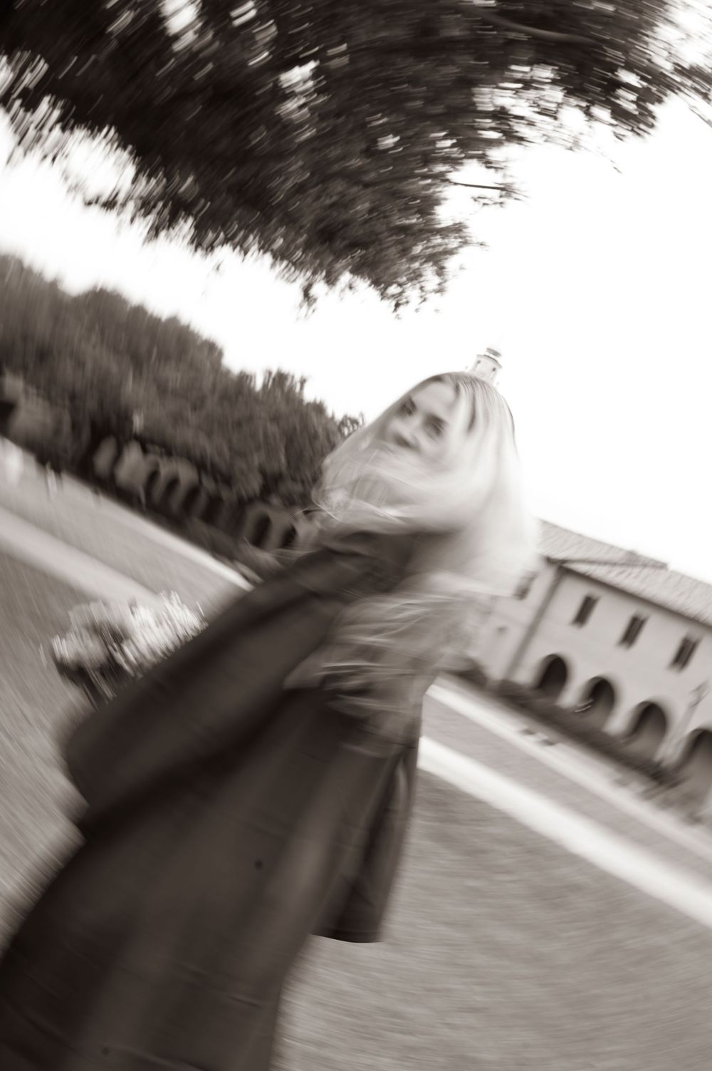 A series of black and white motion-blurred photographs showing an architectural structure with arches in a landscape setting.