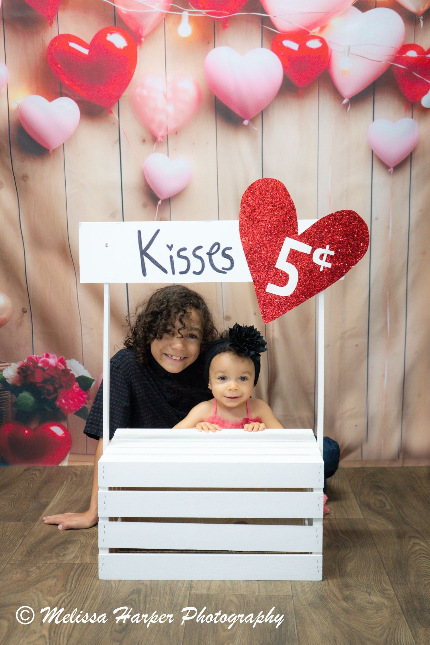 Valentine's themed kissing booth photo setup with red and pink heart decorations.