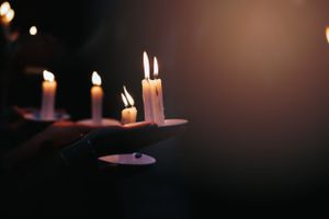 Burning white candles glowing in the darkness with soft bokeh effect.