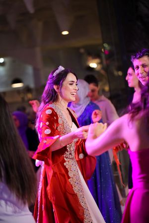 Woman in a stunning red and white embroidered dress dancing joyfully at a celebration.