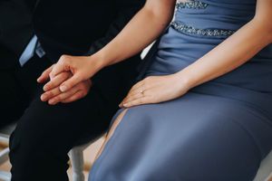Close-up of hands resting on blue formal attire during a special event.