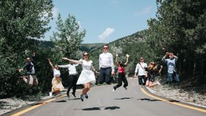 Group jumps simultaneously on a mountain road for a fun photo.