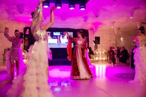 Dancing silhouettes in formal wear under dramatic purple lighting at a wedding reception.
