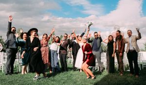 Group celebrates outdoors with enthusiastic poses and jumps against blue sky.
