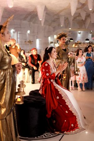 Celebrants in formal attire participate in a ceremony in an elegantly decorated white cave-like venue.