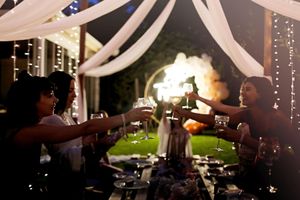 Evening reception under draped fabric with people toasting across a decorated table.
