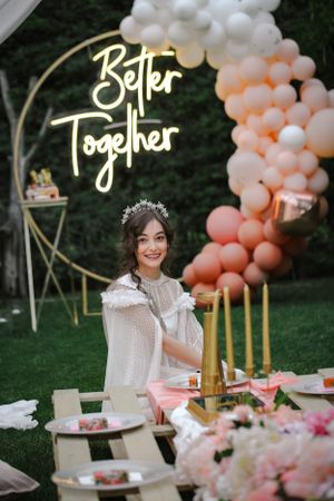 Outdoor wedding decor features balloon arch and 'Better Together' neon sign at garden reception.