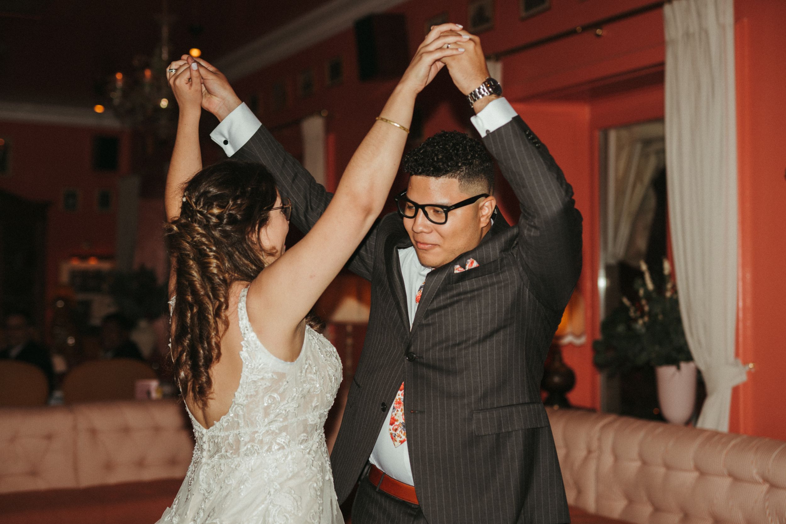 A couple dancing together at their wedding reception, the bride in white and groom in a pinstripe suit.