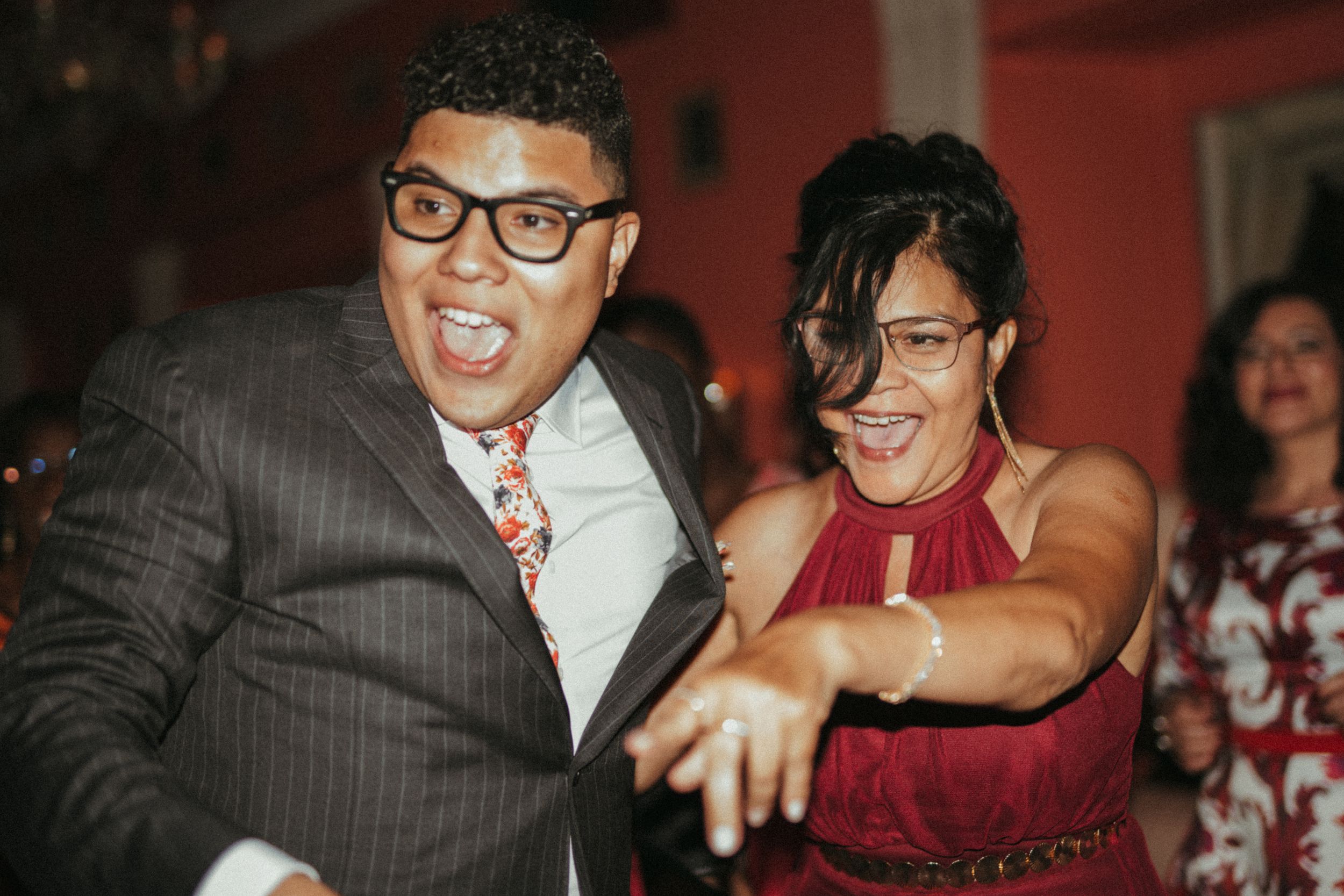 Wedding guests dance and laugh together on the dance floor at a celebration.
