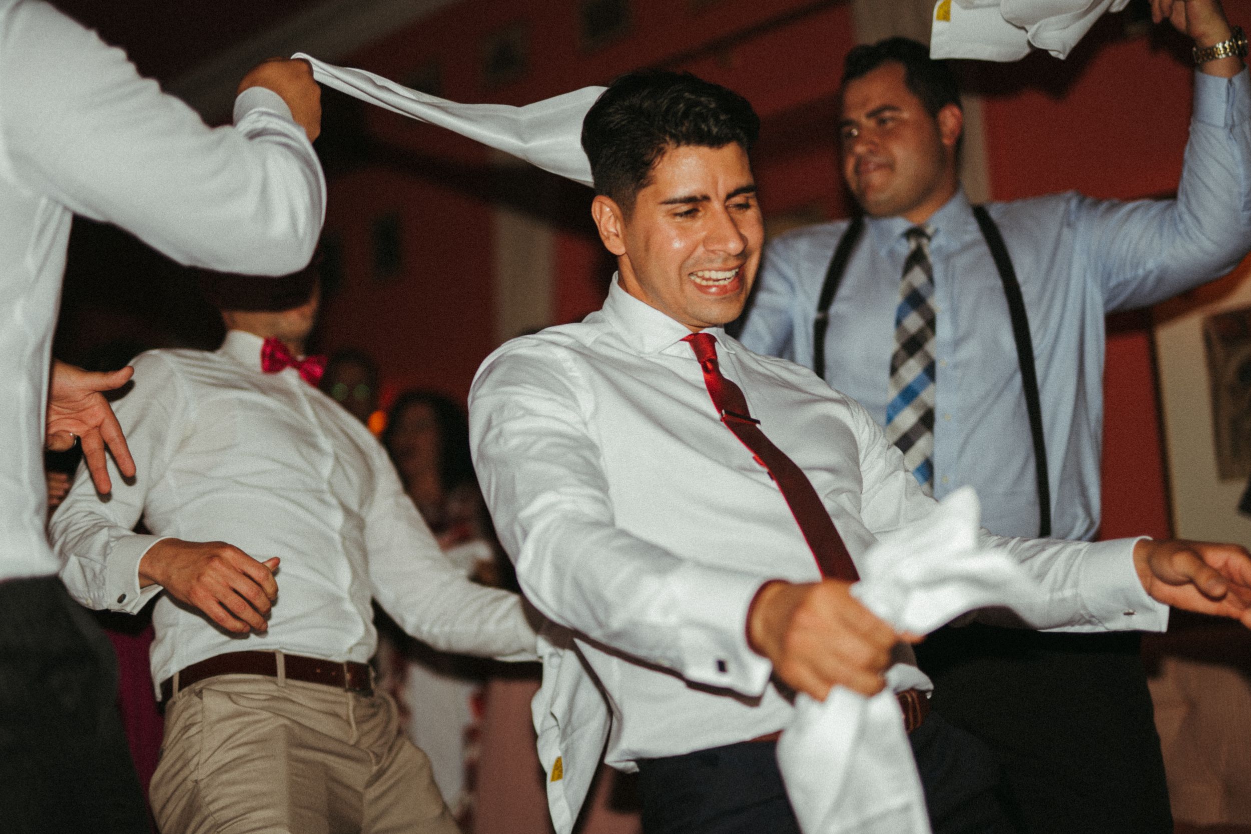 People dancing energetically in formal attire at an indoor celebration.