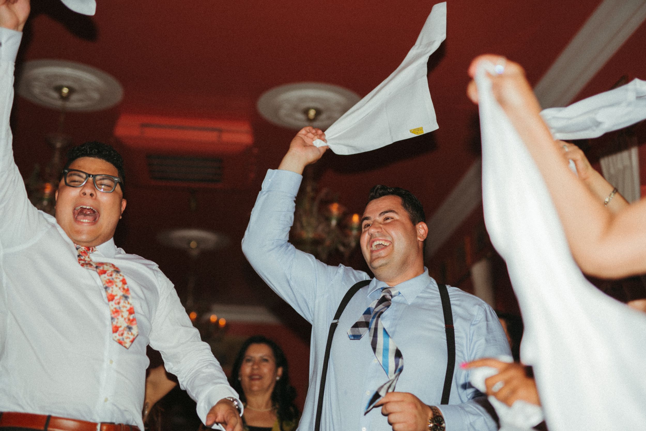 A lively celebration scene at a party with people waving napkins in the air under dim lighting.