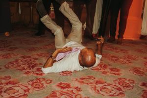 Dancer performs breakdancing move on patterned red carpet during celebration.