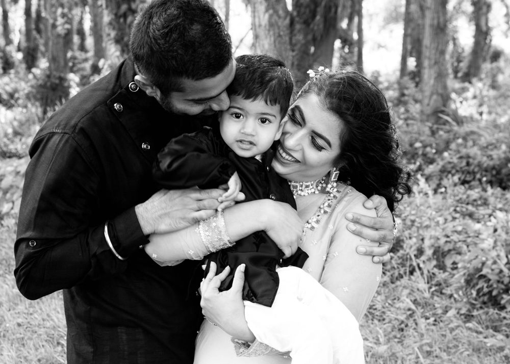 A family shares an intimate moment together while embracing in a wooded forest setting, captured in black and white.