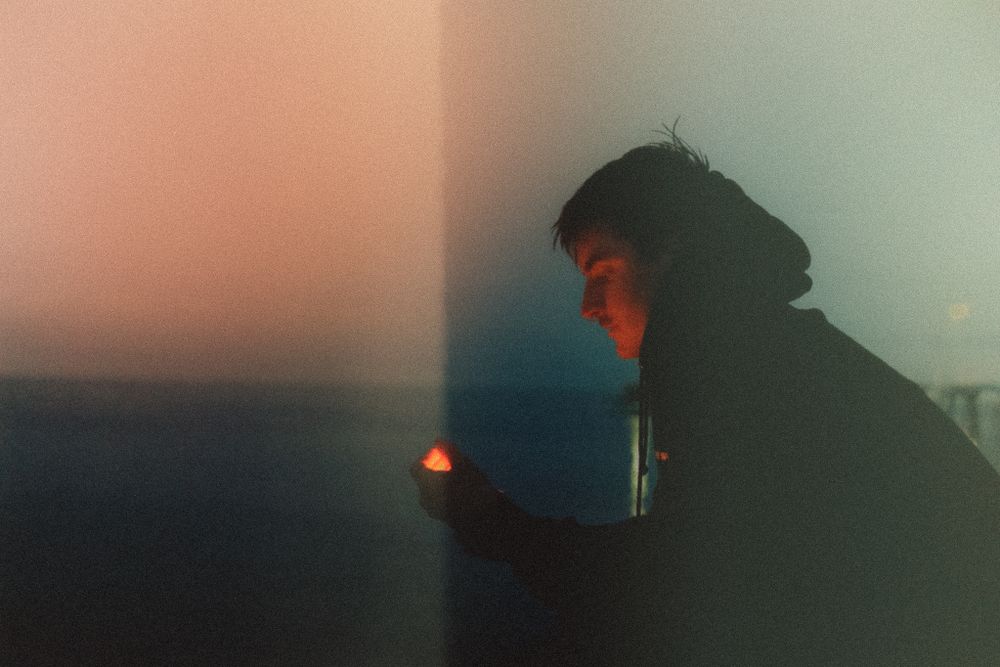 Silhouettes against an orange sunset sky create a moody atmospheric scene.