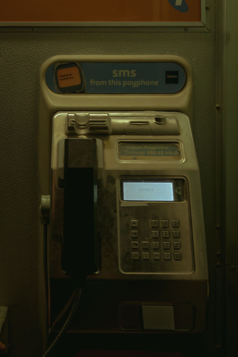 Close-up view of a public payphone keypad and display screen in low light conditions.
