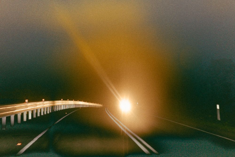 A misty highway at night with street lights creating a moody amber glow.