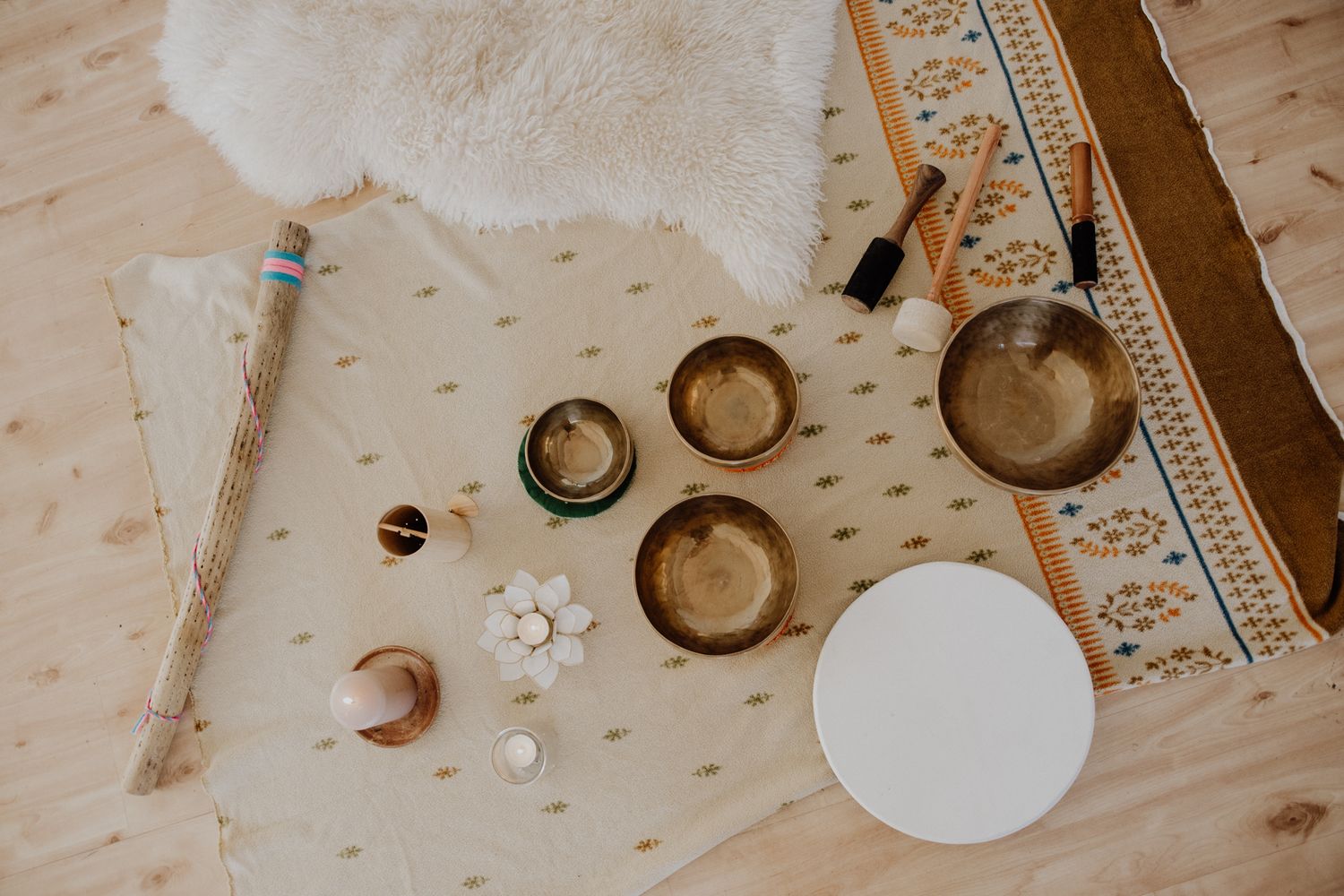 Tibetan singing bowls and meditation tools arranged on a light wooden surface with decorative trim.