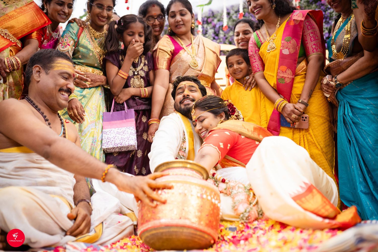 Festive celebration during a traditional Hindu wedding ceremony with guests gathered around ritual items and flower petals.
