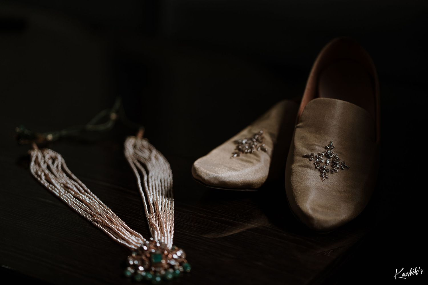 Wedding accessories including elegant satin bridal shoes and crystal jewelry photographed against dark background.
