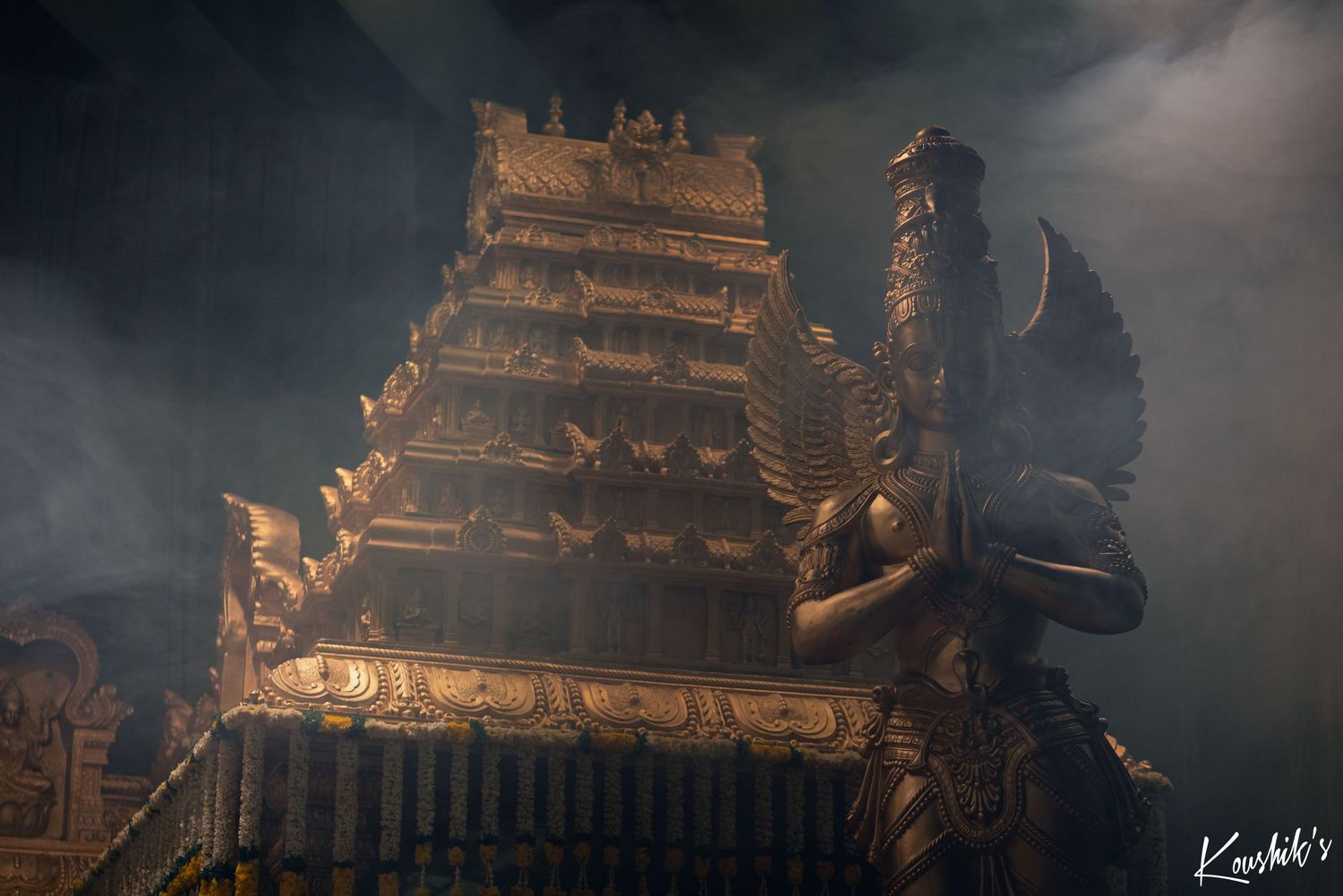 Illuminated golden temple spires emerge through misty darkness creating a mystical atmosphere at night.