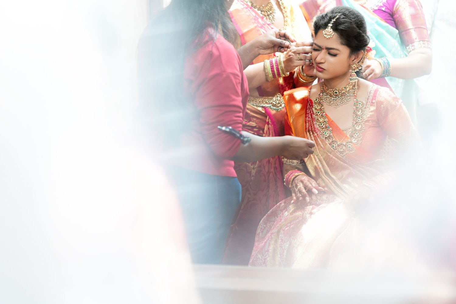 A person in ornate traditional Indian wedding attire participates in a ceremony with soft focus edges.