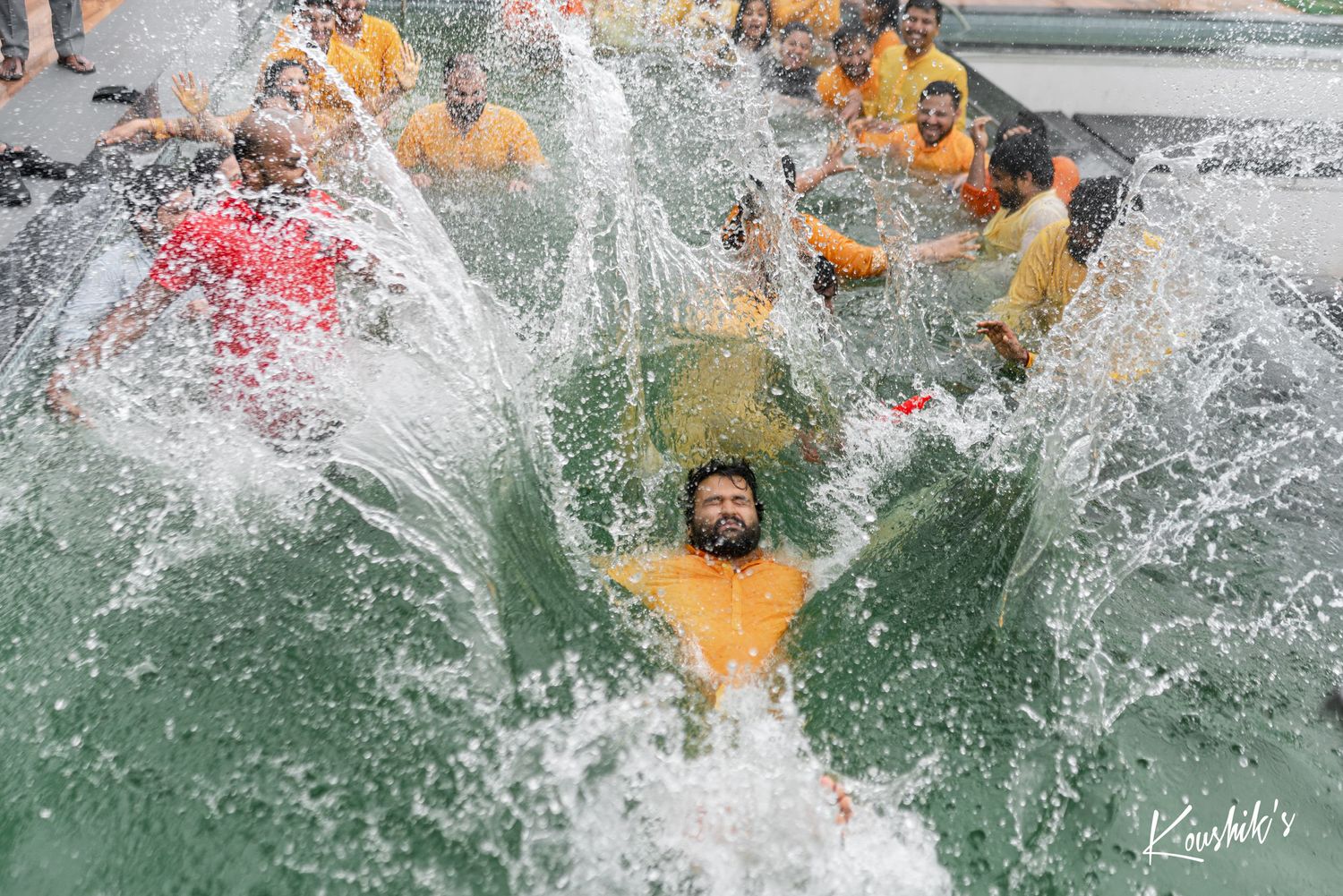 A group of people making a huge splash while jumping into cold water during a polar plunge event.