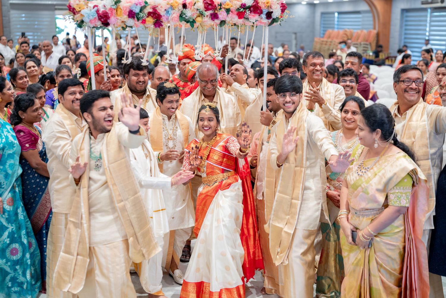 Traditional Indian wedding celebration with balloons, guests in festive cream-colored attire and vibrant decorations.