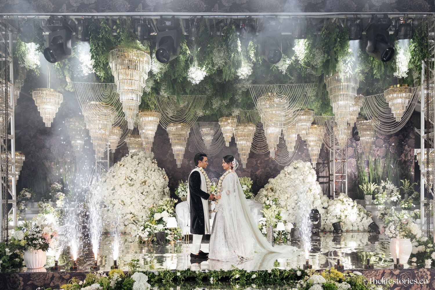 Elegant wedding ceremony setup with cascading crystal chandeliers and white floral arrangements creating a romantic atmosphere.