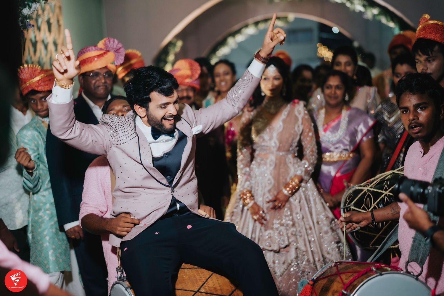 Wedding guests dance and celebrate energetically at a reception with festive décor and a lively party atmosphere.